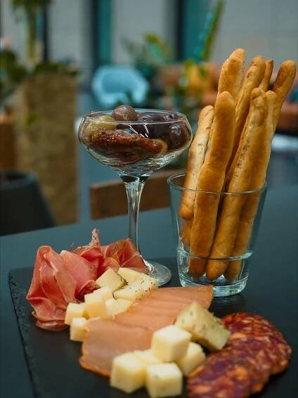 an assortment of cheeses, meats and bread sticks on a table