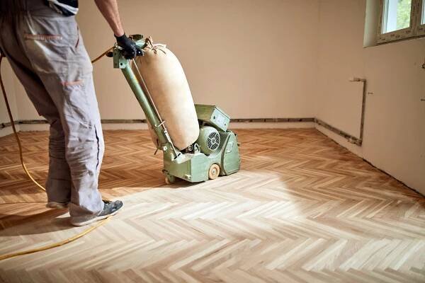 Repairman restoring parquet with a sanding machine..jpg