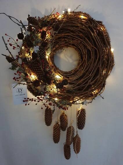 a wreath made out of branches and pine cones with lights hanging from the front end