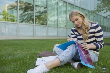 College student doing homework on campus lawn