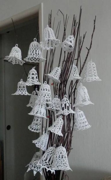 there are many white bells hanging from the tree in front of the door with no leaves on it