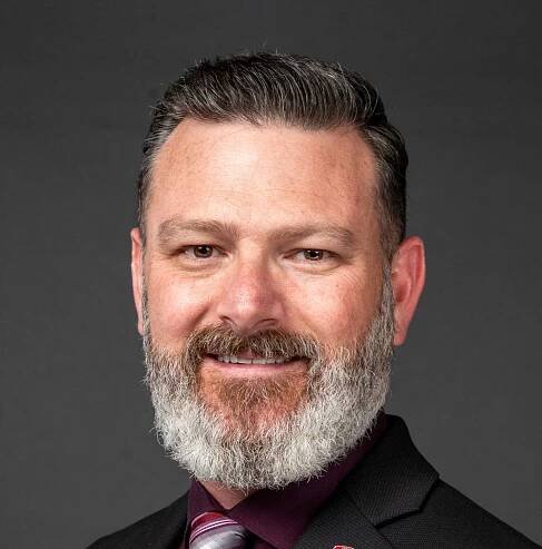 A man with a beard smiling at the camera.