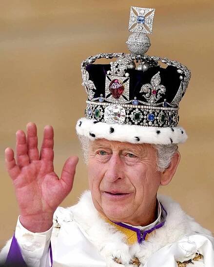 King Charles III waves as he receives a royal salute from members of the military in the gardens of Buckingham Place in London