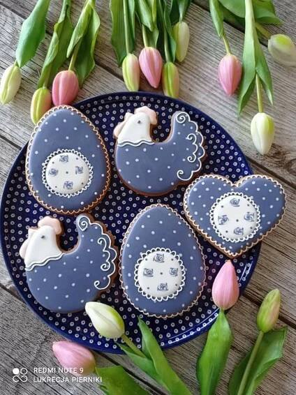 decorated cookies on a blue plate with tulips and flowers in the back ground