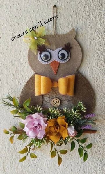 an owl is hanging on the wall with flowers