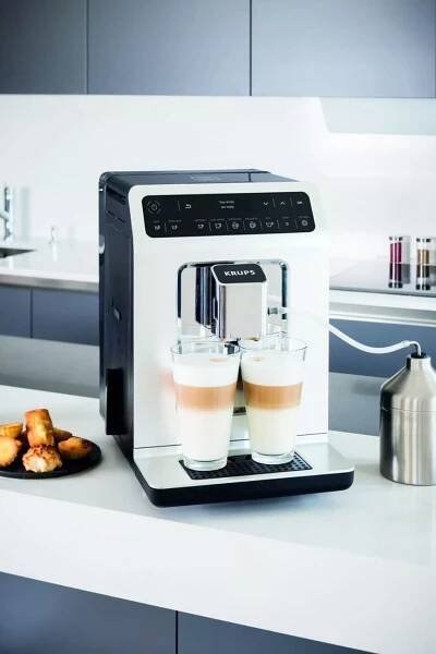 an espresso machine sitting on top of a counter next to two cups of coffee