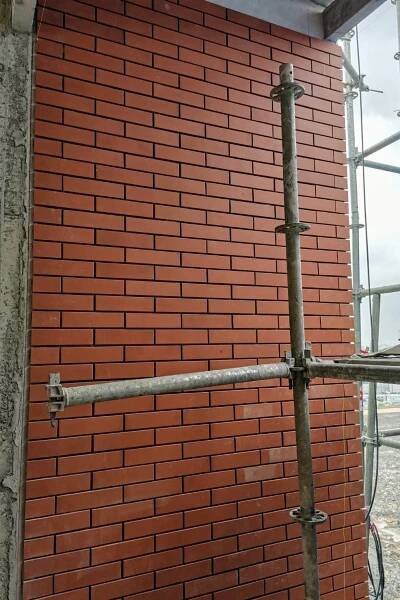 a red brick wall with scaffolding around it and a metal pole attached to the side