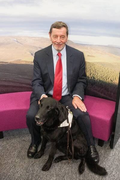 a man in a suit and red tie sits with a black dog