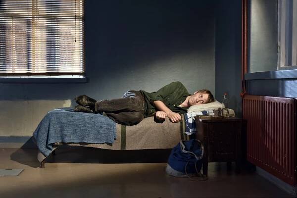a man laying on a small bed in scene from film Fallen Leaves