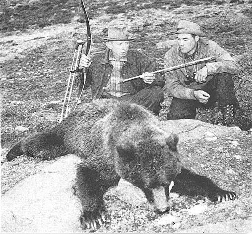 Fred Bear sits behind a grizzly he killed with a bow, in a black and white photo