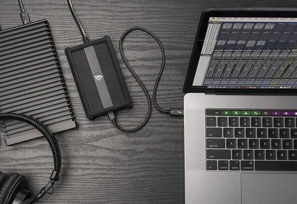 OWC Thunderbolt 4 10G Ethernet Adapter on desktop with OWC Envoy Ultra, Apple MacBook Pro, and headphones