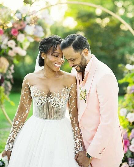 Anika Noni Rose and Jason Dirden Laughing in Front of Flower-Covered Arch