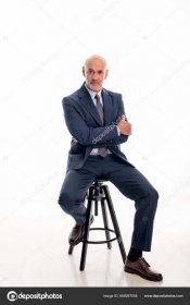 Download - Full length of mid aged man wearing suit and sitting against isolated white background. Confident businessman looking thoughtful. Copy space. — Stock Image