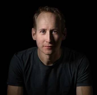 Lukáš Bauer na portrétní fotografii na černém pozadí.