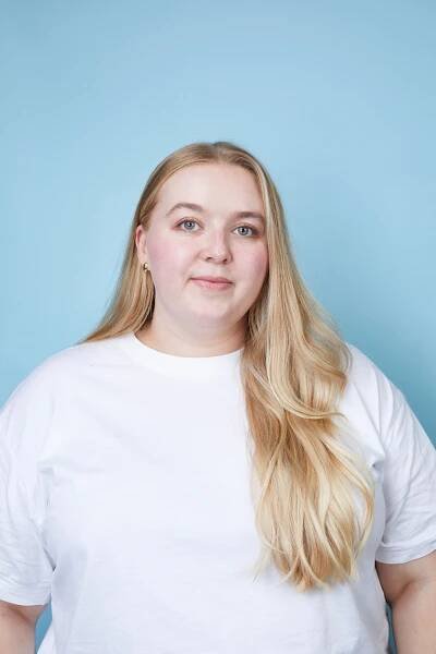 Woman with long blond hair wearing a white t-shirt.