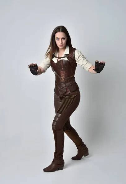 Po celé délce portrét bruneta dívka, která nosí hnědé kožené steampunk oblečení. představovat stojící na šedé studio pozadí. — Stock obrázek