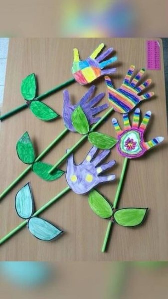 handprinted flowers and leaves on a table with colored pencils next to them