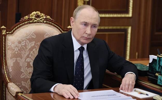 Vladimir Putin listening to a report at a meeting in the Kremlin.