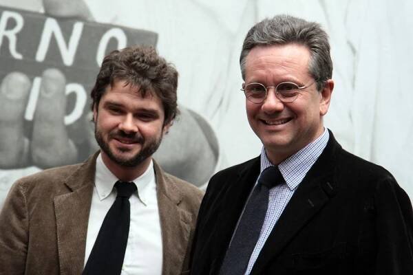Two men wearing suits and ties at an exhibition in 2011