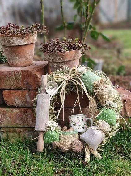 some pots and plants are sitting in the grass near a brick wall with a potted planter on top