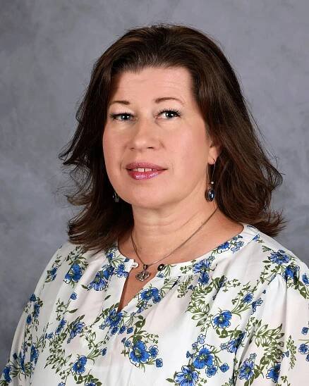a woman wearing a red shirt and a plaid vest is smiling for the camera .