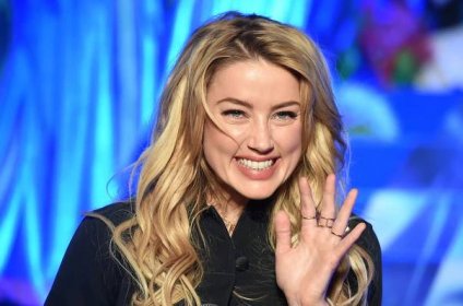 'Aquaman' star Amber Heard holding her hand up waving and smiling