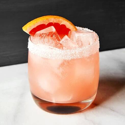 A salty dog cocktail in a rocks glass with a grapefruit garnish.