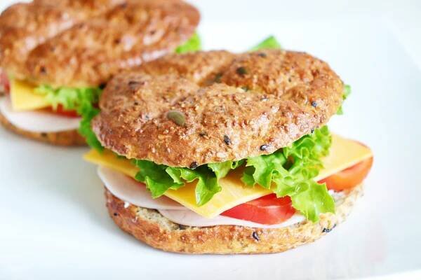 two sandwiches with lettuce, tomato and cheese are on a white platter