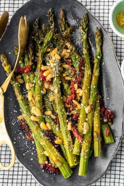 El espárrago asado al horno con tomates secados al sol, piñones, ajo y más es un delicioso plato de inspiración mediterránea para cualquier ocasión. ¡Esta receta fácil de espárragos asados ​​es rápida de preparar pero llena de sabor! Agregue esta guarnición de espárragos a sus comidas navideñas, o simplemente a sus cenas entre semana. De cualquier manera, ¡seguramente será un éxito!
