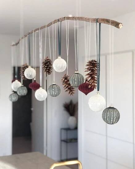 a wind chime with pine cones and ornaments hanging from it's side in a kitchen