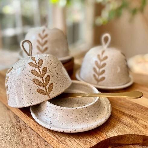 three ceramic dishes with designs on them are sitting on a wooden table next to a spoon