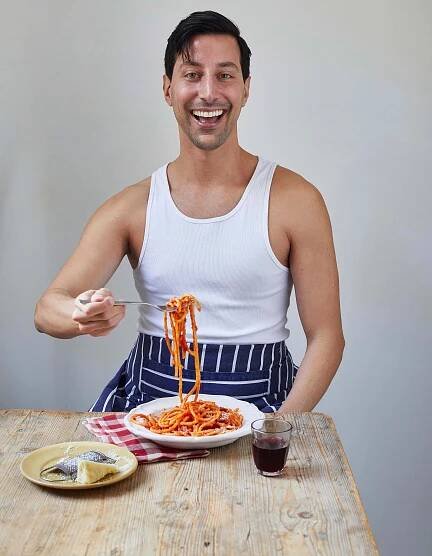a man in a white tank top is eating spaghetti with a fork