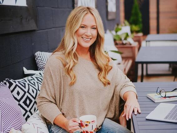 Jennifer Thompson holding a cup of coffee and sitting at her laptop.