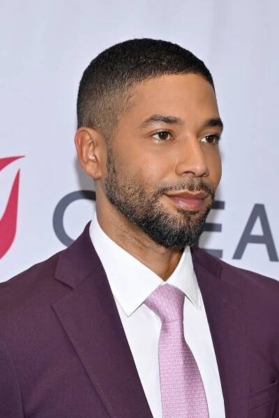 Jussie Smollett in a mauve suit and patterned pink tie at a formal event
