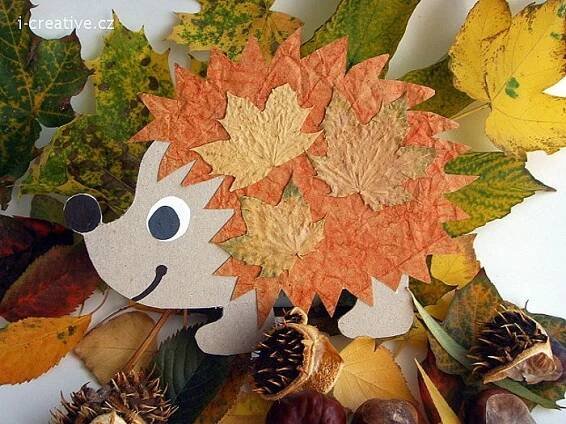 a hedgehog made out of leaves and acorns is surrounded by autumn leaves