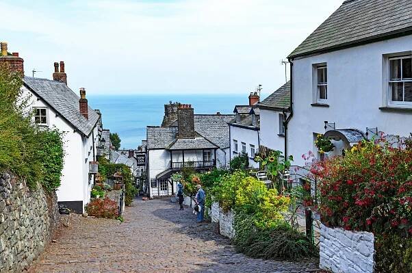 Cobblestone street in Clovelly, Devon, England, with whitewashed houses and ocean view.