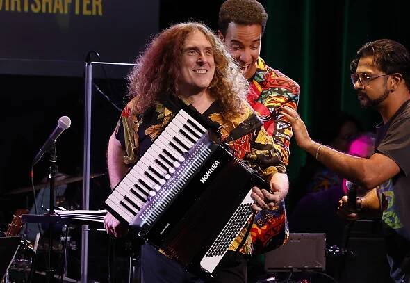 "Weird Al" Yankovic playing an accordion onstage.