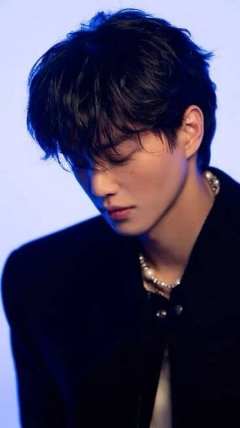 a young man with black hair wearing a suit and pearls on his collared shirt