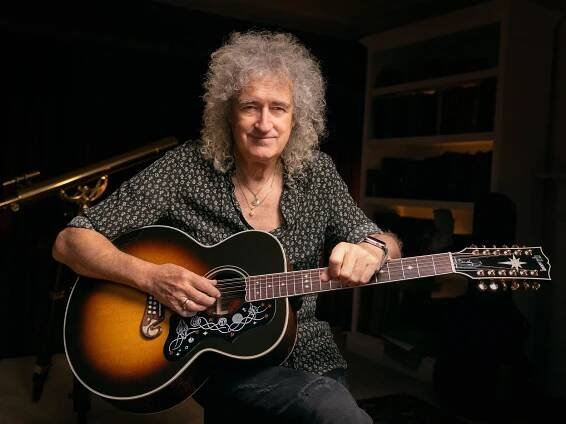 Brian May holding his SJ-200 on his lap and smiling.