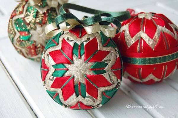three red and green christmas ornaments sitting on top of a white wooden table next to each other
