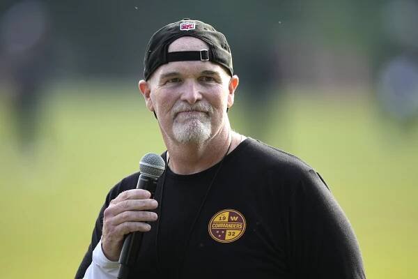 Dan Quinn, Washington Commanders head coach, speaking into a microphone.