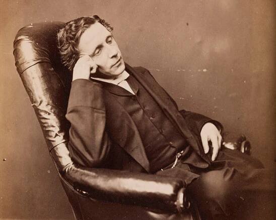 Photograph of Lewis Carroll, circa 1875., showing the author reclining in a chair, resting his head on his hand and wearing a thoughtful expression.