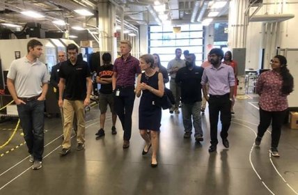 A group of graduate students walk with an industry professionals through an industrial space.