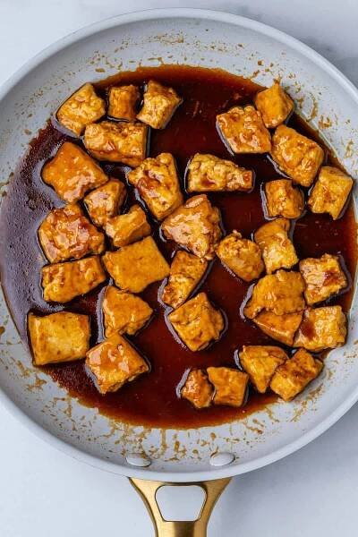 Cooked tofu in a pan covered in teriyaki sauce