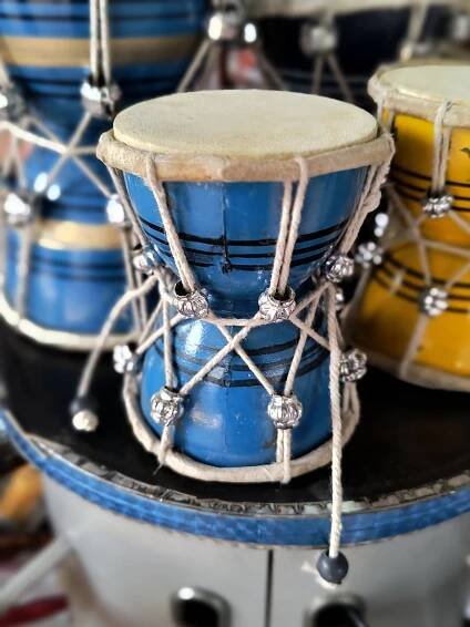 Close-up of a blue and yellow "Shiv Damaru", a traditional instrument associated with Lord Shiva in Hindu mythology.