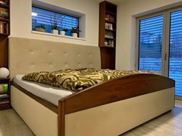 Čalouněná postel s dřevěnými doplňky