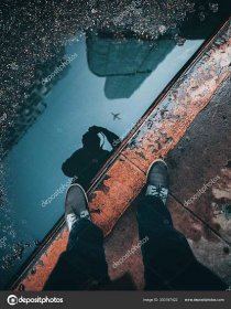Download - A vertical overhead shot of the reflection of a person and buildings in a water puddle — Stock Image