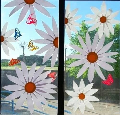 the window is decorated with paper flowers and butterflies