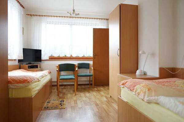 a bedroom with two beds and a desk and a window at Penzion u lázní in Velké Losiny