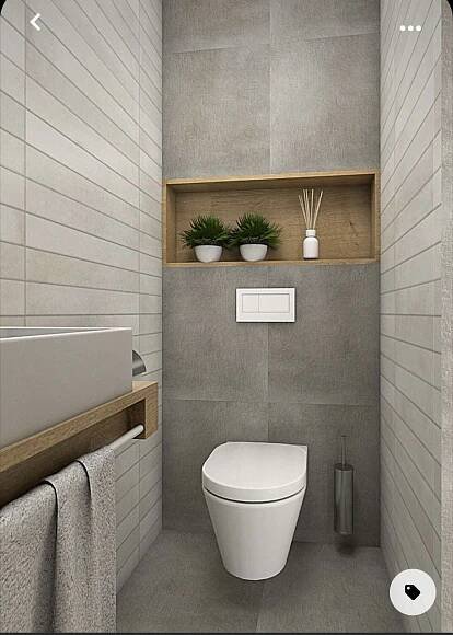 a white toilet sitting inside of a bathroom next to a wooden shelf filled with plants